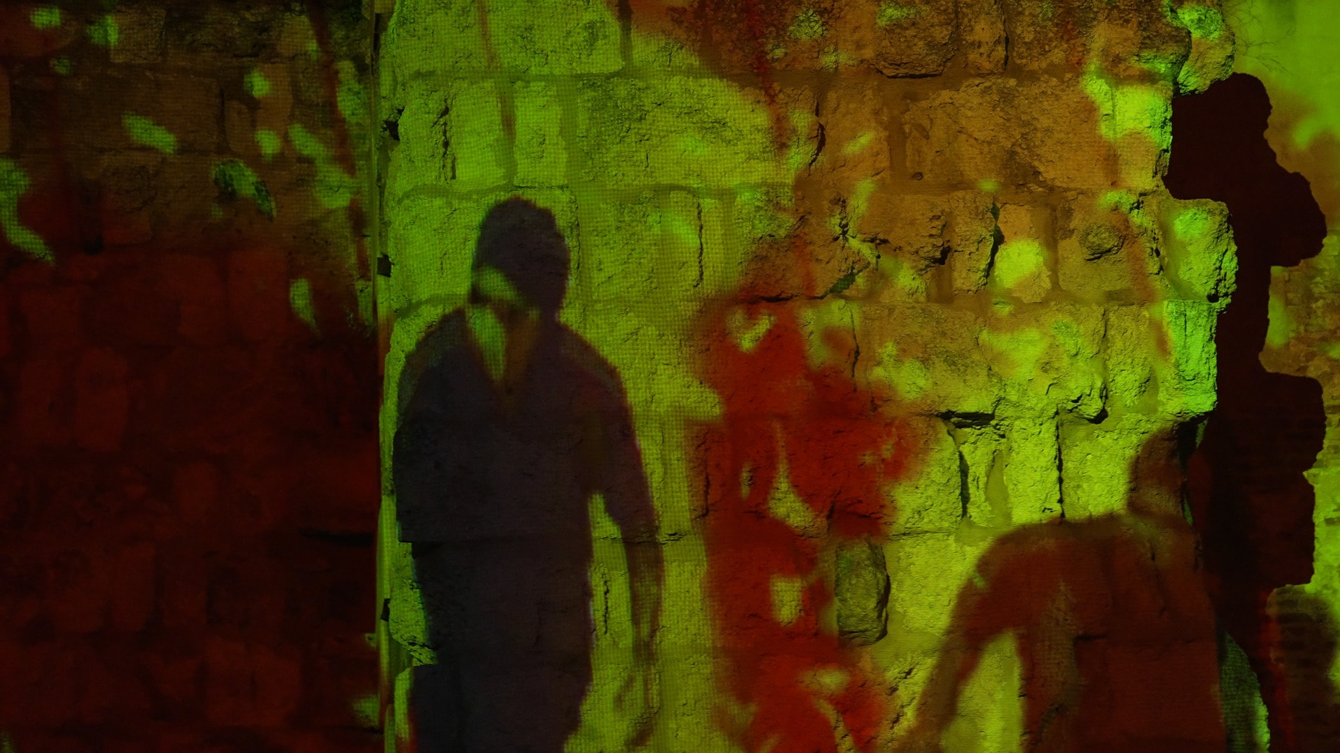 Visitor shadows cast over the projected stone of the Arab wall
