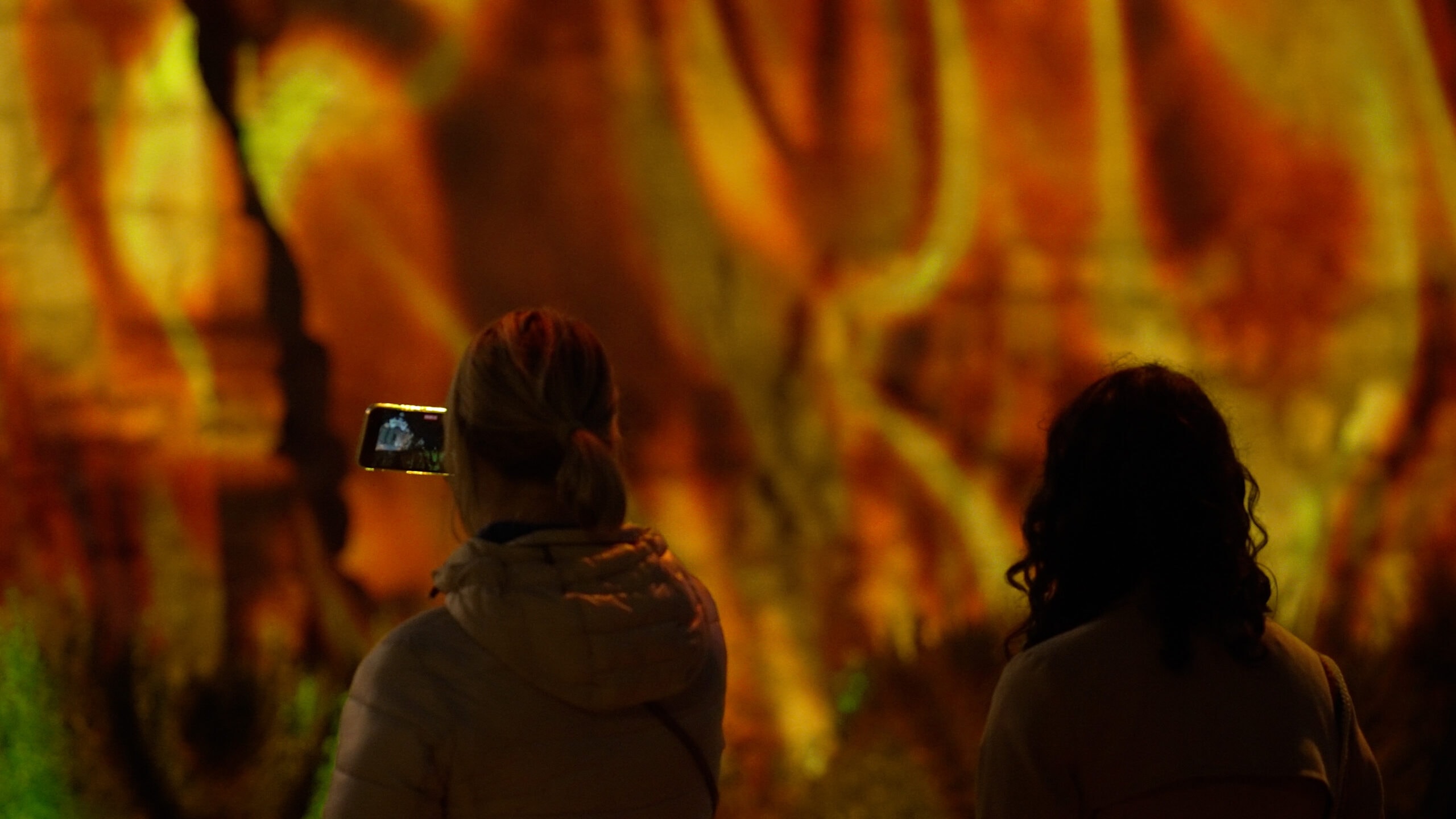 Two visitors silhouetted against the projected wall at Mayrit