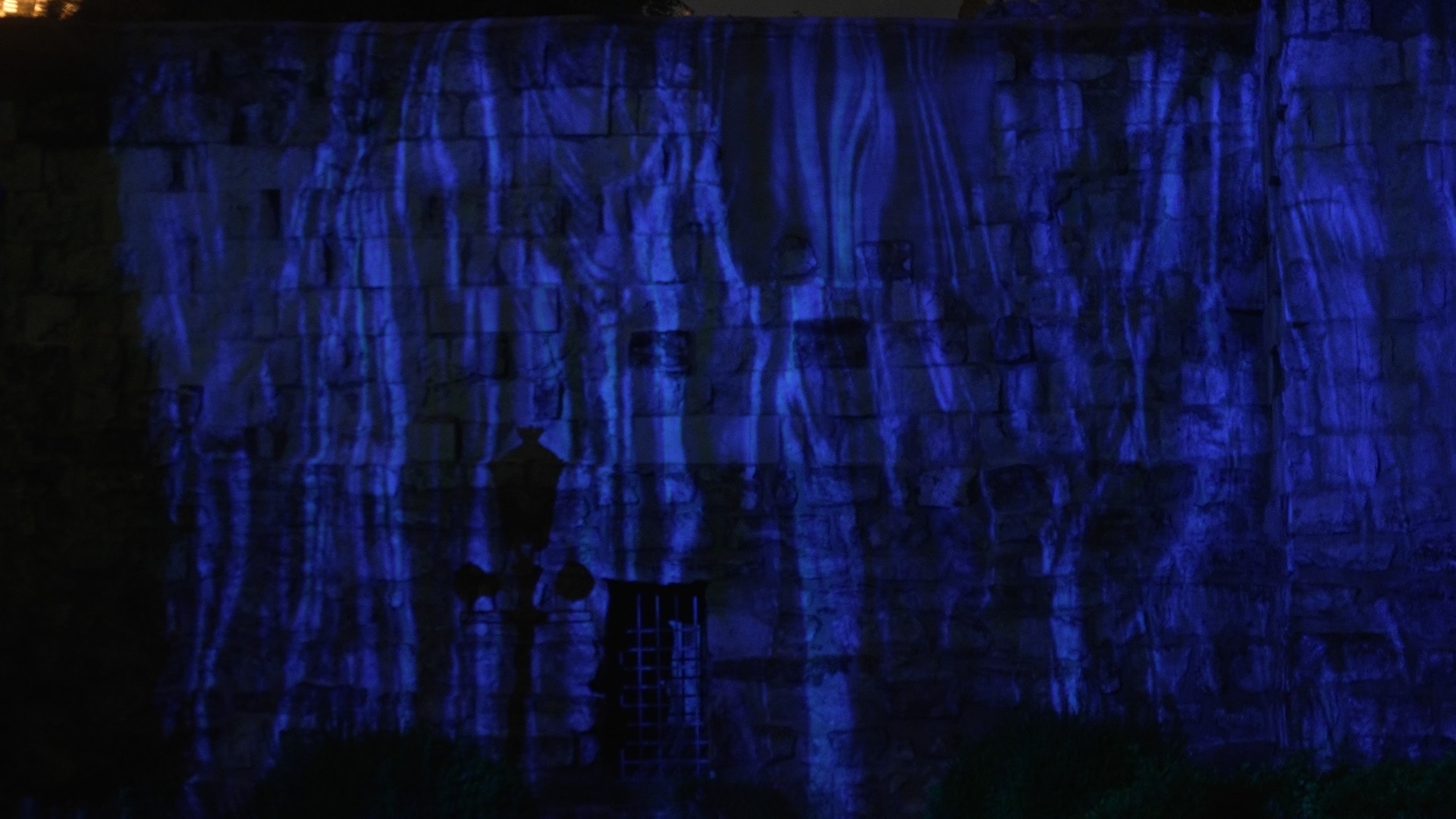 Water-like generative pattern projected across the wall in blue